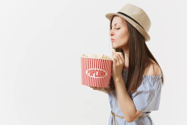 Mavi elbiseli, yeme patlamış mısır kova tutarak film film izlerken şapka genç kadın beyaz arka plan üzerinde izole. İnsanlar, sinema, yaşam kavramı samimi duygular. Reklam alanı. Kopya alanı