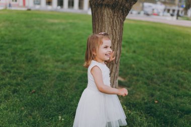 Küçük şirin çocuk bebek kız ışıkta gülüyor stand elbise ve şehir parkı yeşil çim ağaçta bulman. Anne, küçük çocuk kızı. Anneler günü, aşk aile, ebeveynlik, çocukluk kavramı