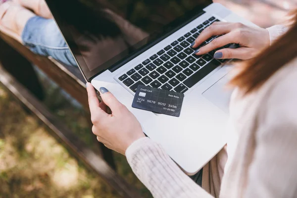 Klavye üzerinde eller yukarı kapatın. Modern dizüstü pc bilgisayar Şehir Park Caddesi'nde açık havada çalışan bir kredi kartı, holding bankta oturan kadın. Mobil ofis. Online alışveriş, iş kavramı