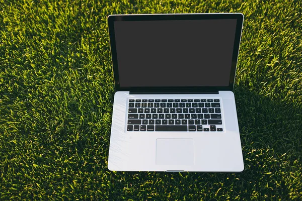Dizüstü pc bilgisayar boş siyah Boþ ekran alanı kopyalamak için park canlı bahar yeşil taze çimenlerin üzerinde açık havada doğa üzerinde güneş çim çayır ile kapatın. Mobil ofis. Serbest iş kavramı
