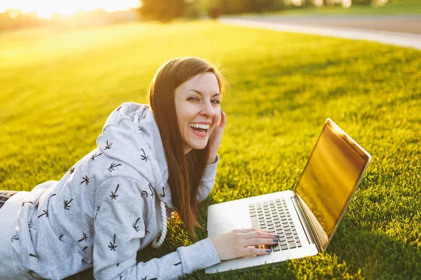Genç öğrenci rahat kıyafetler içinde kadın akıllı. Çim, dizüstü pc bilgisayar Şehir Park açık havada Güneş çim yeşil çim üzerinde üzerinde çalışıyor yatan kadın. Mobil ofis. Serbest iş kavramı