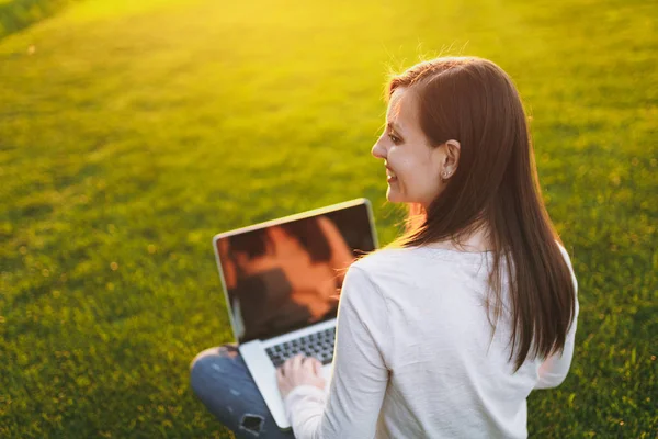 Genç kadın arkadan görünüm. Şehir Parkı yeşil çim Güneş'ın bahçesinde açık havada, uzay kopyalamak için dizüstü pc bilgisayar boş siyah Boþ ekran ile üzerinde çalışan kadın. Mobil ofis. Serbest iş kavramı