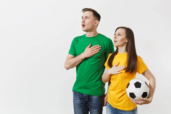 感情的なカップル 女性の男性 黄色緑 シャツ元気づける白い背景に分離されたサッカー ボール歌国立国国歌とサポート チームのサッカーファン スポーツ レジャー ライフ スタイル — ストック写真