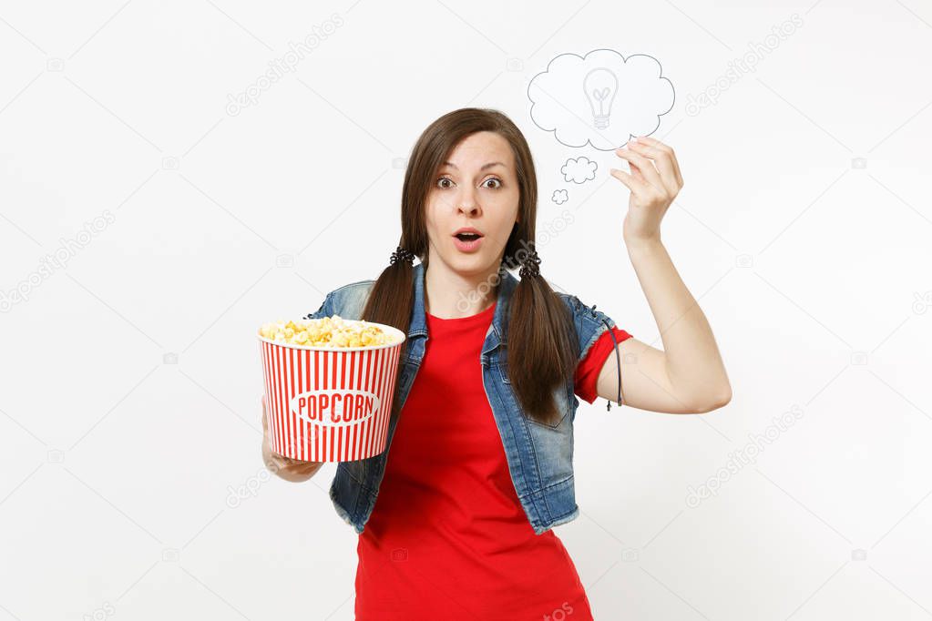 Portrait of young shocked woman in casual clothes watching movie film, holding say cloud with lightbulb, idea and bucket of popcorn isolated on white background. Emotions in cinema concept
