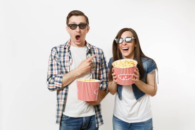 Genç çift, kadın ve erkek 3d gözlük ve rahat kıyafetler tarihte, film film izlerken patlamış mısır, gülüyor, poiting parmağı beyaz arka plan üzerinde izole kova tutarak. Sinema duygular
