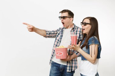 Young shocked couple, woman and man in 3d glasses watching movie film on date, holding bucket of popcorn and plastic cup of soda or cola isolated on white background. Emotions in cinema concept clipart