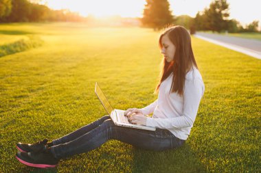 Genç öğrenci kadın rahat kıyafetler. Dizüstü pc bilgisayar Şehir Park açık havada Güneş çim yeşil çim üzerinde çalıştığı yer, çimenlerin üzerinde oturan bir bayan. Mobil ofis. Serbest iş kavramı