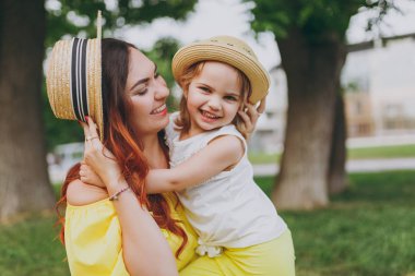 Kadın sarı elbise kucaklama gülüyor, küçük şirin çocuk bebek kız oyun ile kucaklamak ve yeşil park eğlenmek. Anne, küçük çocuk kızı. Anneler günü, aşk aile, ebeveynlik, çocukluk kavramı