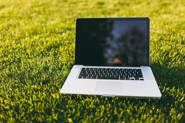 Dizüstü pc bilgisayar boş siyah Boþ ekran alanı kopyalamak için park canlı bahar yeşil taze çimenlerin üzerinde açık havada doğa üzerinde güneş çim çayır ile kapatın. Mobil ofis. Serbest iş kavramı