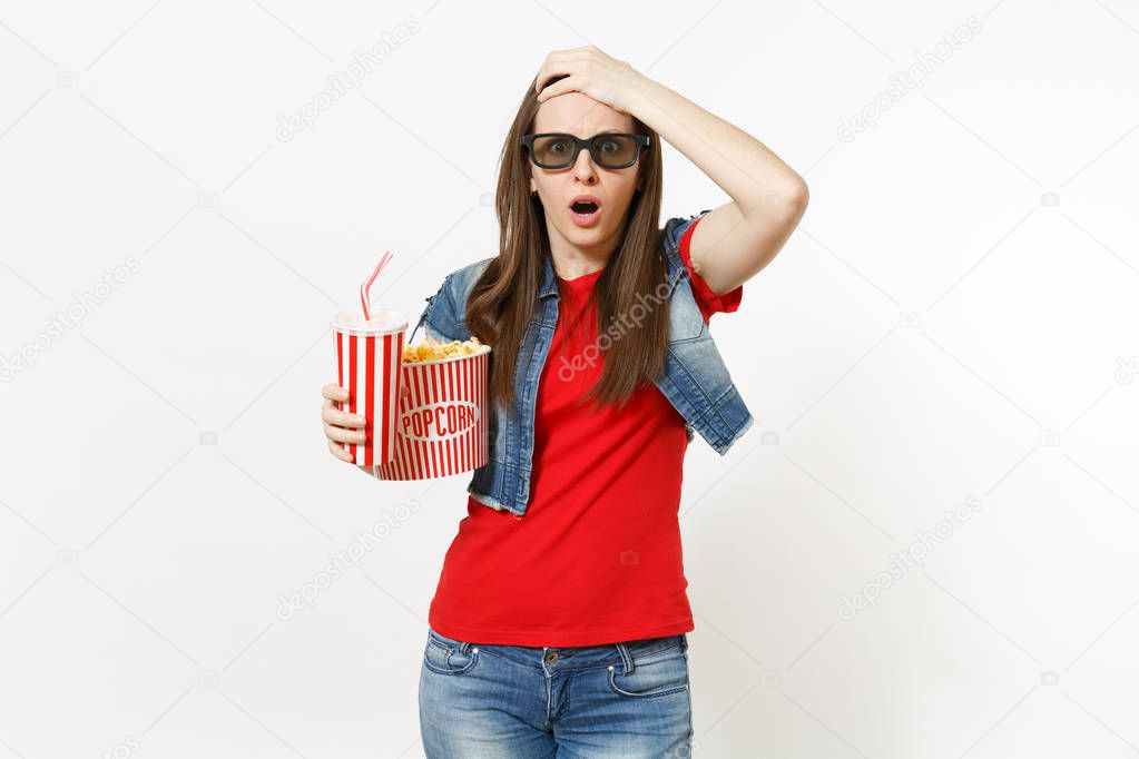 Portrait of young shocked woman in 3d glasses watching movie film, holding bucket of popcorn and plastic cup of soda or cola, clinging to head isolated on white background. Emotions in cinema concept