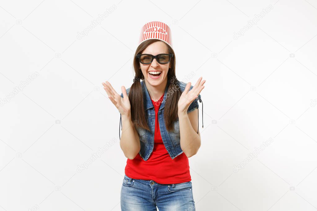 Portrait of young smiling attractive woman in 3d glasses and casual clothes with bucket for popcorn on head watching movie film and spreading hands isolated on white background. Emotions in cinema