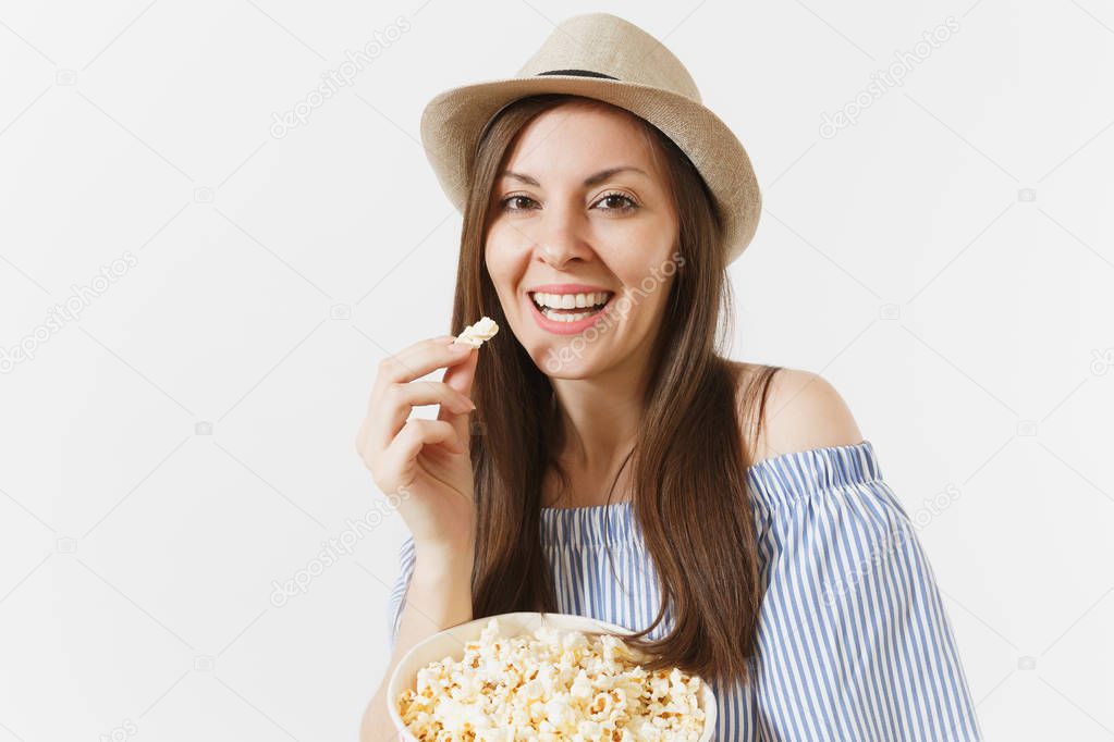 Young woman in blue dress, hat watching movie film holding eating popcorn from bucket isolated on white background. People, sincere emotions in cinema, lifestyle concept. Advertising area. Copy space