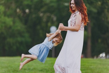 Işık elbiseli kadın ve Park yeşil çim çim üzerinde çember oynarken küçük şirin çocuk bebek kız gülümsüyor. Anne, küçük çocuk kızı. Anneler günü, aşk aile, ebeveynlik, çocukluk kavramı