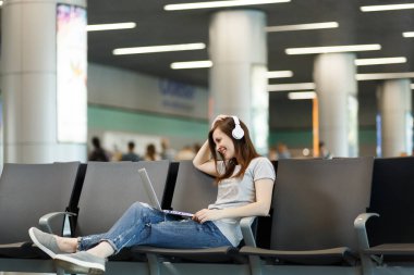 Dizüstü bilgisayar, çalışma müzik dinlerken kulaklık ile seyahat etmek turist gülümseyen genç Uluslararası Havaalanı'nda lobi salonunda bekleyin. Hafta sonu kaçamağı yurt dışında seyahat yolcu. Hava uçuş kavramı