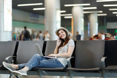 Dizüstü bilgisayarda çalışan genç rüya gibi gezgin turist kadın üstünde hareket eden telefon, çağrı arkadaş, taksi, otel bekle lobi salonunda havaalanında rezervasyon konuş. Yurt dışında hafta sonları seyahat yolcu. Hava uçuş kavramı