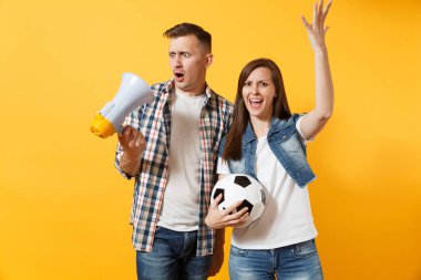 Kızgın eğlenceli expessive çift, çığlık, kadın erkek futbol taraftarları destek ekibi ile futbol topu, sarı zemin üzerine izole megafon neşelendirmek. Spor aile eğlence kavga sorun yaşam tarzı kavramı
