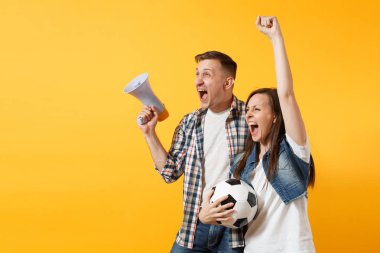 Mutlu genç çift destekçisi, kadın erkek, futbol taraftarları destek ekibi, tezahürat megafon, sarı zemin üzerine izole futbol topu tutan. Spor, aile eğlence, insanların yaşam tarzı kavramı