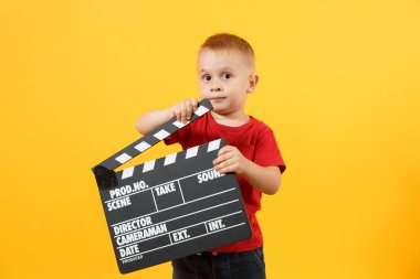Küçük sevimli oğlu kırmızı t-shirt elinde tutan Klaket görünümlü kamera classik siyah film 3-4 yaşında sarı arka plan üzerinde izole. Çocuklar çocukluk yaşam tarzı kavramı. Kopya alanı
