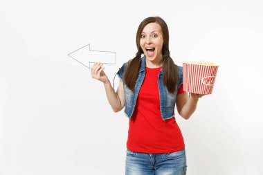 Film film izlerken, kova patlamış mısır holding, beyaz ok bir kenara beyaz arka plan üzerinde izole boşaltmak üzerinde işaret eden rahat kıyafetler genç çok memnun kadın portresi. Sinema kavramı duygular