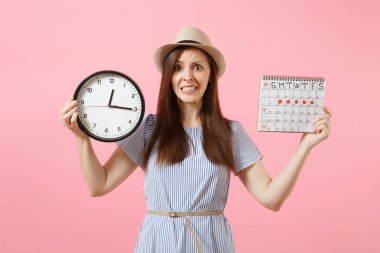Yuvarlak saat, pembe eğilimleri arka plan üzerinde izole adet gün kontrol etmek için dönemleri takvim tutan mavi elbiseli şok karışık üzgün kadın. Tıbbi jinekolojik kavramı. Kopya alanı