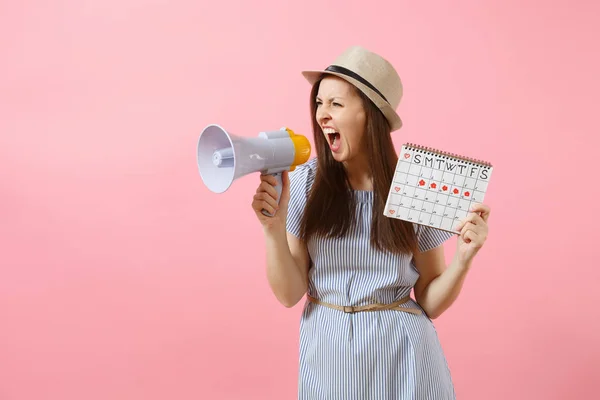 Angry expression wild woman screaming in megaphone, holding periods calendar for checking menstruation days isolated on pink background. Medical healthcare, pms mood gynecological concept. Copy space