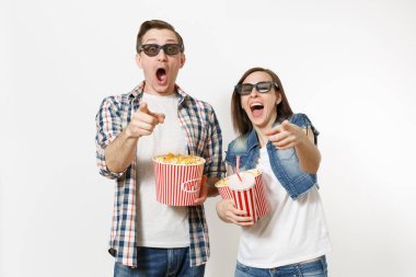 Genç çift, kadını ve kova patlamış mısır, bardak kola veya kola, işaret parmağı kamera işaret tutan adam 3d gözlük tarihte, film film izlerken beyaz arka plan üzerinde izole. Sinema duygular