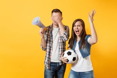 Kızgın eğlenceli expessive çift, çığlık, kadın erkek futbol taraftarları destek ekibi ile futbol topu, sarı zemin üzerine izole megafon neşelendirmek. Spor aile eğlence kavga sorun yaşam tarzı kavramı