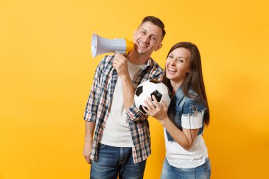 Mutlu genç çift destekçisi, kadın erkek, futbol taraftarları destek ekibi, tezahürat megafon, sarı zemin üzerine izole futbol topu tutan. Spor, aile eğlence, insanların yaşam tarzı kavramı