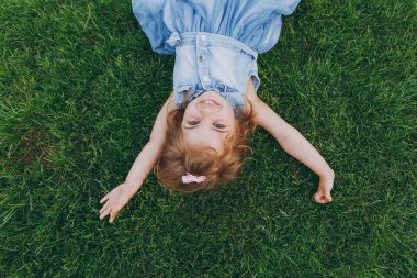 Neşeli küçük güzel çocuk bebek kız park ellerinde yayılan ışık elbise yalan yeşil çim çimenlikte. Anne, küçük çocuk kızı. Anneler günü, aşk aile, ebeveynlik, çocukluk kavramı