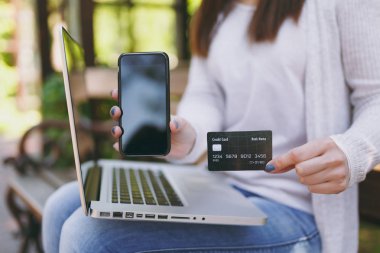 Kamera kredi kartı, cep telefonu alan kopyalamak için boş boş ekran ile gösterilen kadın. Açık havada sokakta modern dizüstü bilgisayar üzerinde çalışan bankta oturan kadın. Mobil ofis. Serbest iş kavramı