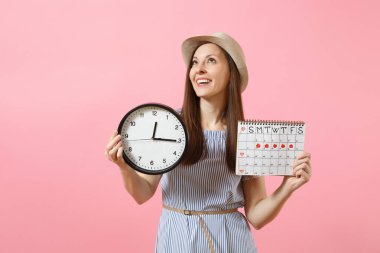 Gülümseyen güzel kadın mavi elbiseli, şapka saat, holding dönemleri takvim adet gün kontrol etmek için pembe bir arka plan eğilimleri izole. Tıbbi sağlık jinekolojik kavramı. Kopya alanı