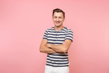 Heyecanlı gülümseyen yakışıklı genç adam tutuşup çizgili tişört giyen portresi katlanmış pembe eğilimleri arka plan üzerinde izole geçti. İnsanlar samimi duygular yaşam tarzı kavramı. Reklam alanı