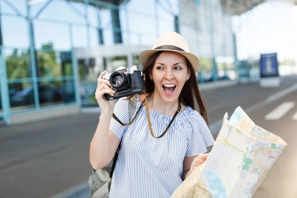 レトロなビンテージ写真カメラ 国際空港で紙の地図を持って帽子の若い楽しい旅行観光女 女性の乗客は 週末の息抜きに旅行に海外旅行します 空気飛行概念 — ストック写真