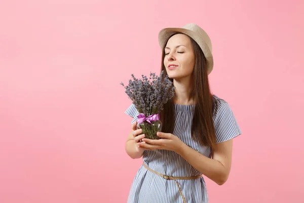 Portrait of a happy young tender woman in blue dress, hat holding bouquet of beautiful purple lavender flowers isolated on bright trending pink background. International Women Day holiday concept
