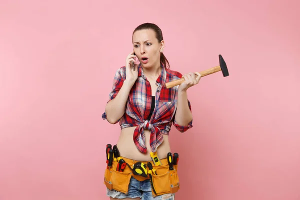 愤怒的杂工妇女在格子衬衫套件工具腰带充满乐器交谈的手机 进行不愉快的谈话 在粉红色的背景孤立 女性在男性工作 装修理念 — 图库照片