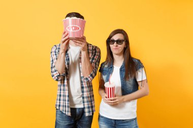 Genç memnun çift kadın adam 3d gözlük yüz kova patlamış mısır ile kapsayan tarihte film film izlerken içinde plastik bardak kola veya kola izole sarı arka plan üzerinde tutun. Sinema duygular