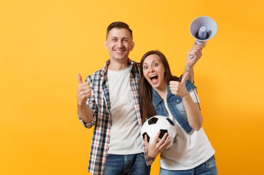 Mutlu genç çift destekçisi, kadın erkek, futbol taraftarları destek ekibi, tezahürat megafon, sarı zemin üzerine izole futbol topu tutan. Spor, aile eğlence, insanların yaşam tarzı kavramı