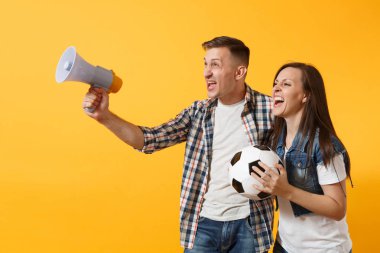 Mutlu genç çift destekçisi, kadın erkek, futbol taraftarları destek ekibi, tezahürat megafon, sarı zemin üzerine izole futbol topu tutan. Spor, aile eğlence, insanların yaşam tarzı kavramı