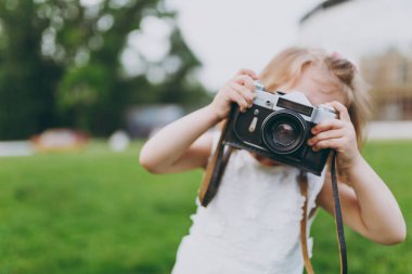 Işık elbiseli küçük şirin çocuk bebek kız parkta yeşil çimenlerin üzerinde retro vintage fotoğraf makinesinde resim çekmek. Anne, küçük çocuk kızı. Anneler günü, aşk aile, ebeveynlik, çocukluk kavramı