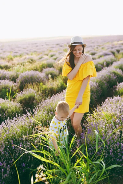 黄色のドレス紫ラベンダー花草原フィールド背景 歩きながら若い女性楽しく かわいい子の小さな男の子と遊ぶ 小さな子供の息子 家族の日 子供たちのコンセプト — ストック写真
