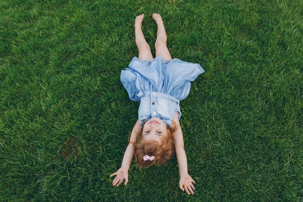 Usmívající Malé Roztomilé Dítě Holčičku Džínové Šaty Leží Zelené Trávě — Stock fotografie