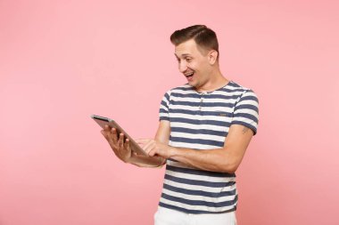 Tablet pc bilgisayarınıza çalışma çizgili tişört giyen Kullanıcı genç adam portresi gidişli pastel pembe arka plan üzerinde izole. İnsanlar samimi duygular yaşam tarzı kavramı. Alan kopya alanı üzerinde reklam