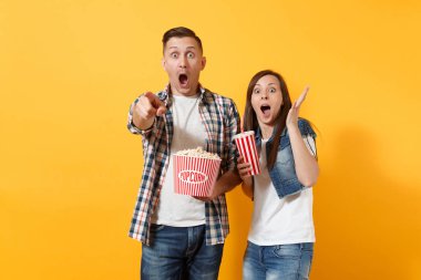 Genç kova patlamış mısır plastik kap kola veya kola el işaret parmağı üzerinde sarı arka plan izole yayılan tutan tarihi film film izlerken kaç kadın adam şaşırttı. Sinema duygular