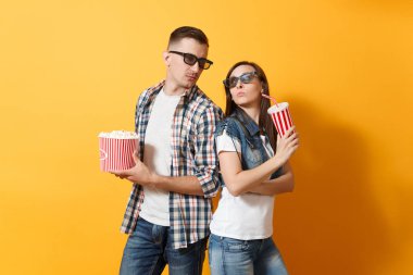 Genç çift kadın adam 3d gözlük kova patlamış mısır plastik kap kola veya kola birbirimize izole sarı arka plan üzerinde seyir tutan tarihi film film izlerken içinde söz konusu. Sinema duygular