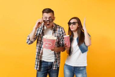 Genç kadın çift ve kova patlamış mısır ve kola veya kola sarı arka plan üzerinde izole plastik bardak tutan tarihi film film izlerken 3d gözlük insanda hayret. Sinema kavramı duygular