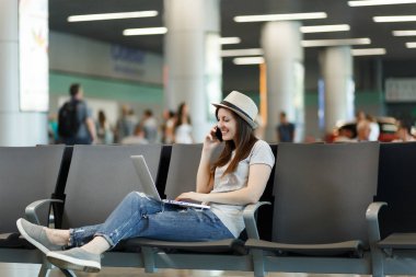 Dizüstü bilgisayarda çalışan genç güzel gezgin turist kadın üstünde hareket eden telefon, çağrı arkadaş, taksi, otel bekle lobi salonunda havaalanında rezervasyon konuş. Yurt dışında hafta sonları seyahat yolcu. Hava uçuş kavramı