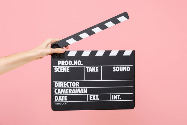 Close up female holding in hand classic director clear empty black film making clapperboard isolated on trending pastel pink background. Cinematography production concept. Copy space for advertising