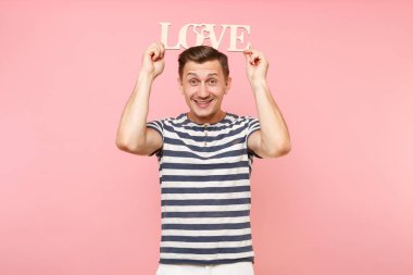 Word'de çizgili tişört ahşap duygusal genç adam portresi izole üzerinde gidişli pastel pembe arka plan seviyorum. İnsanlar samimi duygular yaşam tarzı tatil kavramı. Alan kopya alanı için reklam