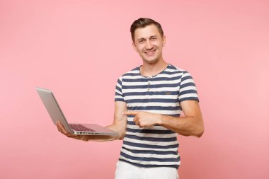Dizüstü bilgisayar, eğilimleri pastel pembe arka plan üzerinde izole kopya alanı üzerinde tişört giyen yakışıklı genç adam portresi çizgili. İnsanlar samimi duygular yaşam tarzı kavramı. Reklam alanı