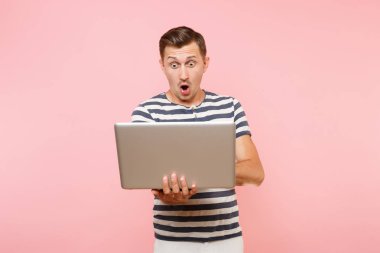 Dizüstü bilgisayar, eğilimleri pastel pembe arka plan üzerinde izole kopya alanı üzerinde tişört giyen üzgün üzgün genç adam portresi çizgili. İnsanlar samimi duygular yaşam tarzı kavramı. Reklam alanı